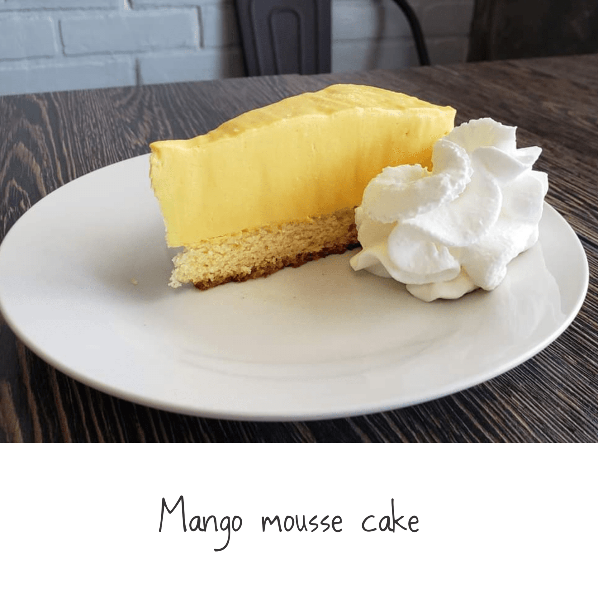 A slice of mango mousse cake with whipped cream on a white plate