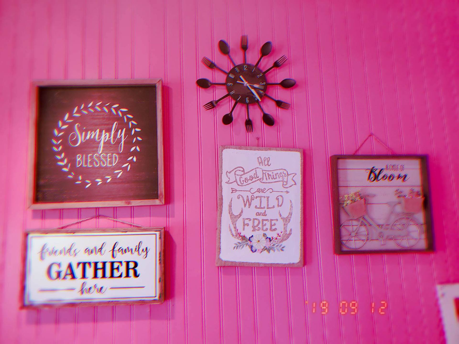 A pink wall with a clock and signs on it.