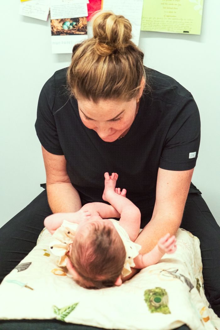 A woman is playing with a baby on a table.