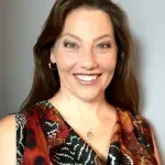 A woman in a floral dress is smiling for the camera.