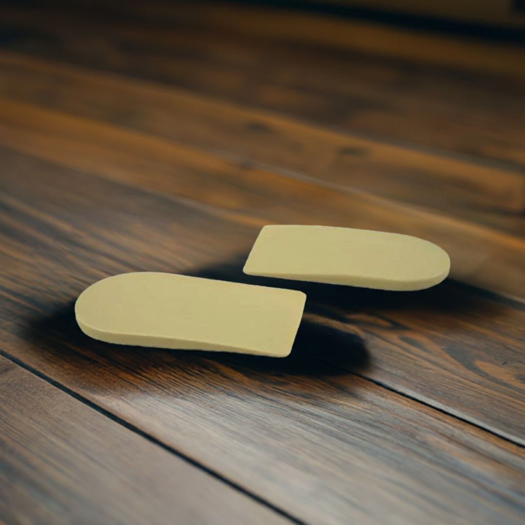 A pair of yellow insoles are sitting on a wooden floor.