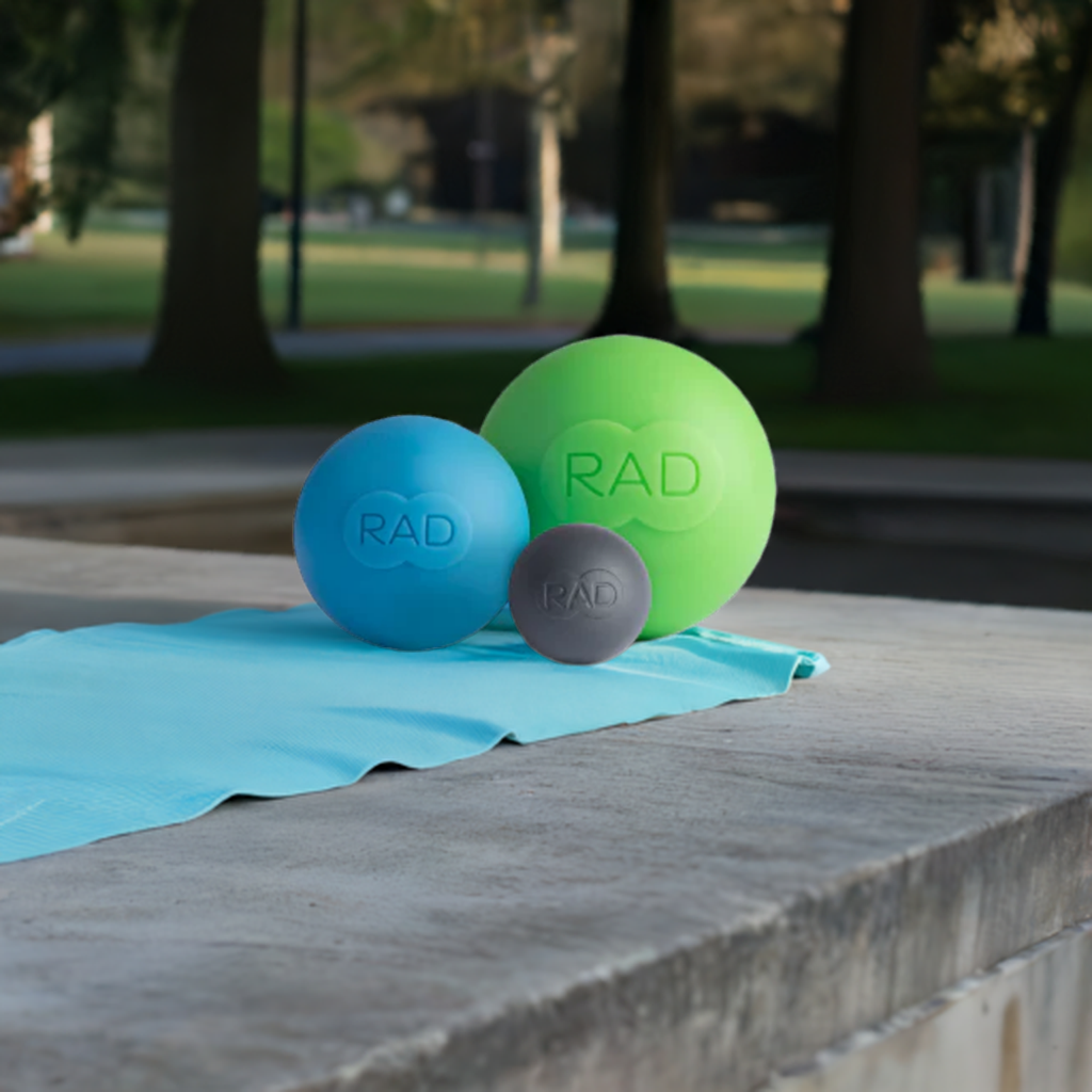 Three rad balls are sitting on a blue towel on a concrete surface.