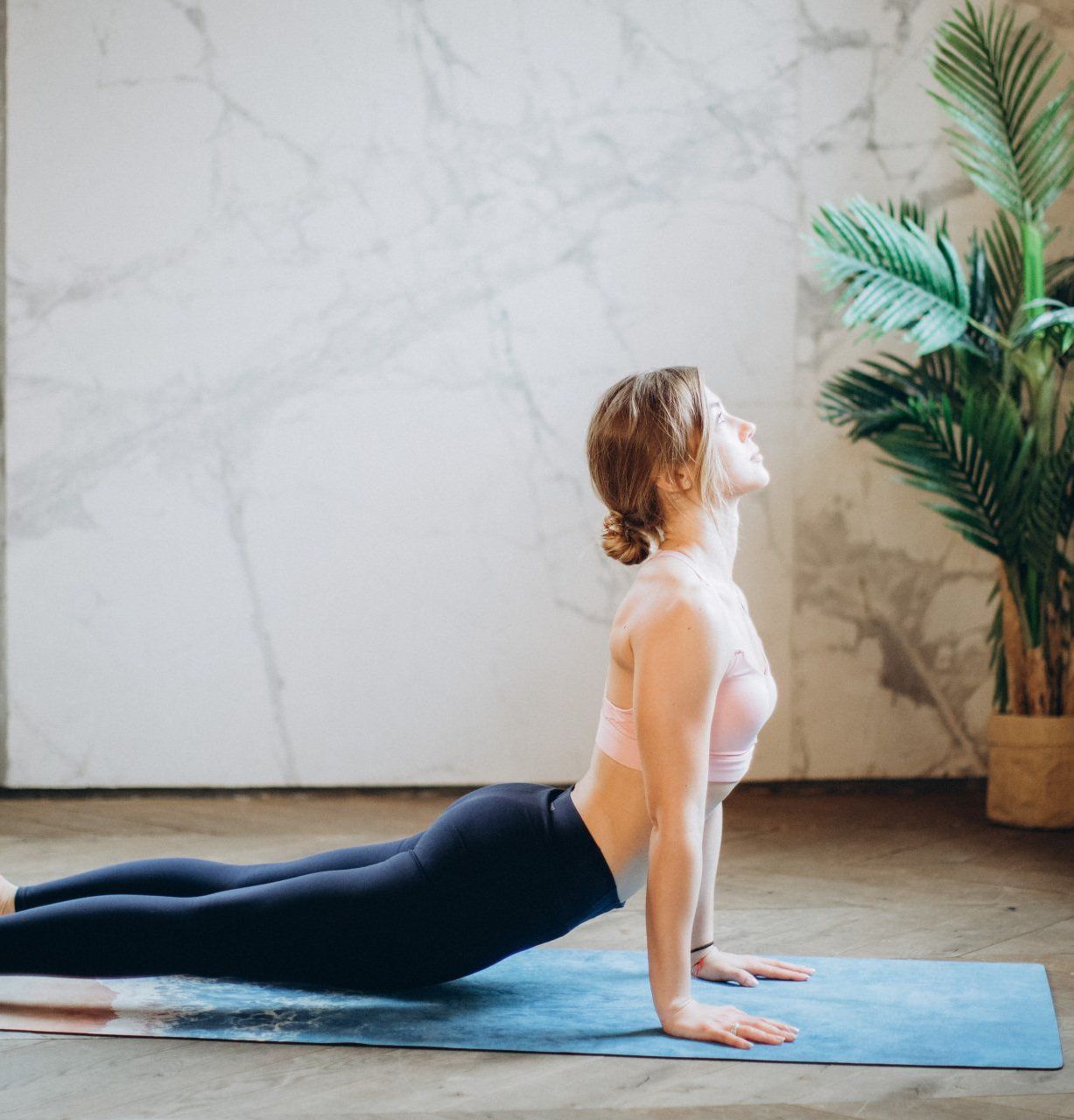 A woman is doing a yoga pose on a blue mat.