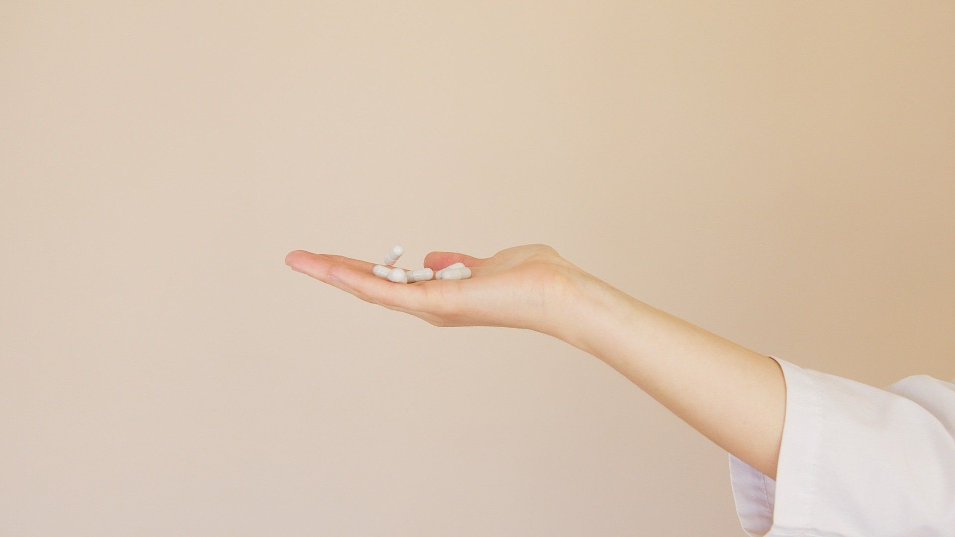 A person is holding a handful of pills in their hand.