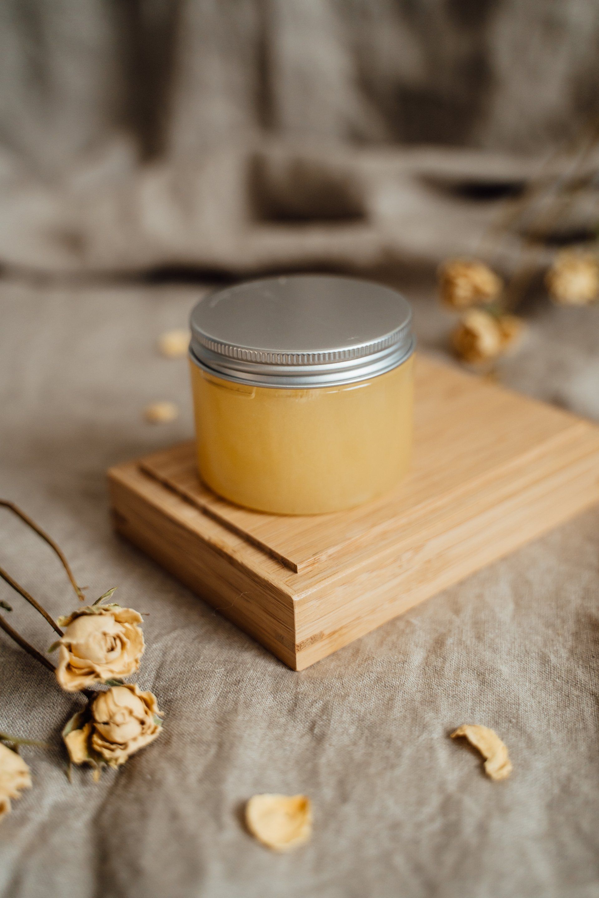 A jar of honey is sitting on top of a wooden tray.