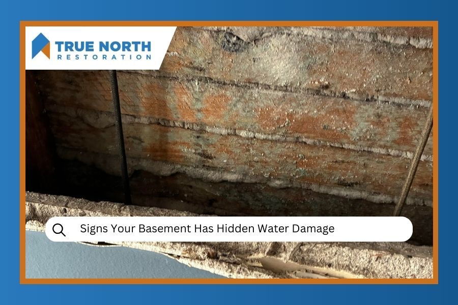 Basement ceiling with water damage, orange and white discoloration, dark lines.