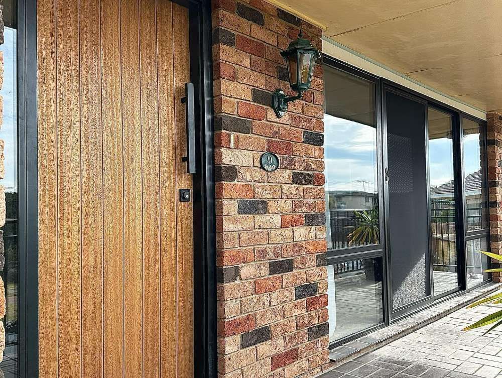 A Brick Building With a Wooden Door and a Lamp — Bespoke Doors & Windows in the Southern Highlands, NSW