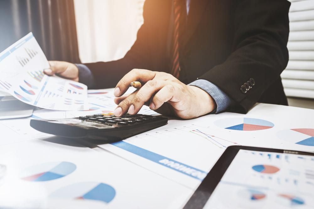 A Man is Sitting at a Desk Using a Calculator and a Pen — SouthMac Finance In Townsville, QLD