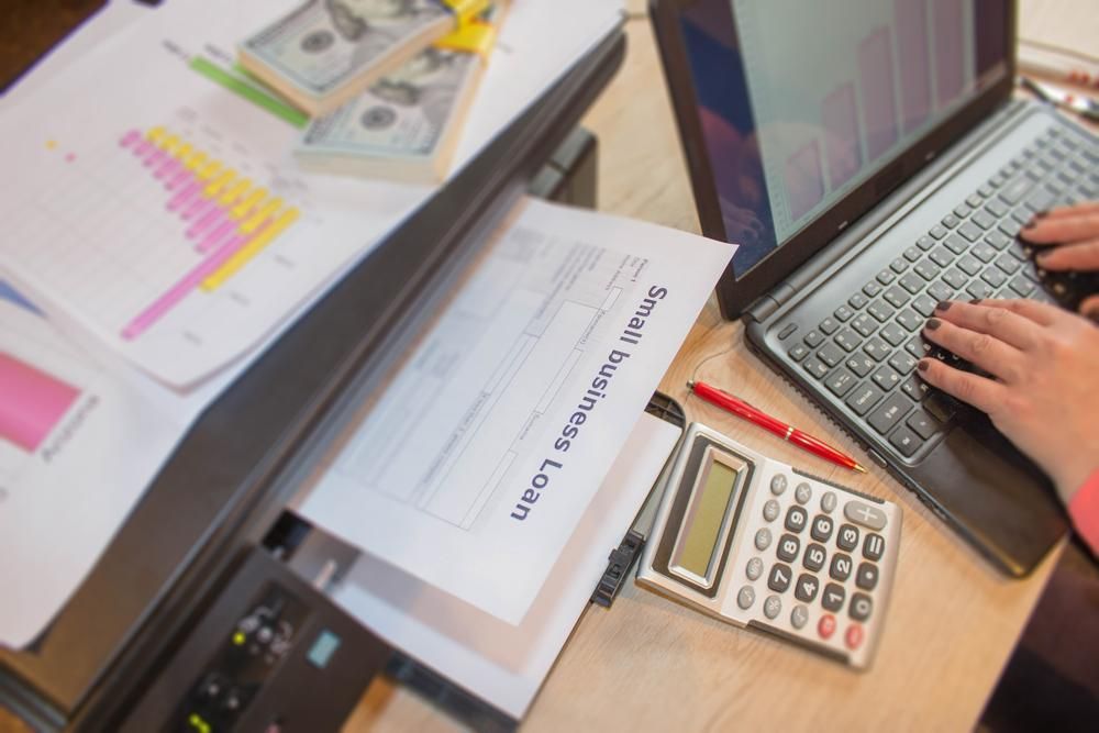 A Person is Typing on a Laptop Next to a Printer and Calculator — SouthMac Finance In Townsville, QLD
