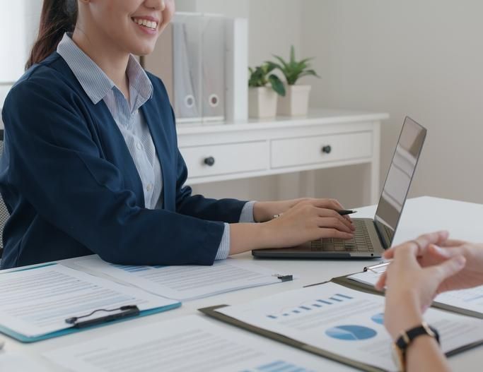 A Woman is Sitting at a Desk Using a Laptop Computer — SouthMac Finance In Townsville, QLD
