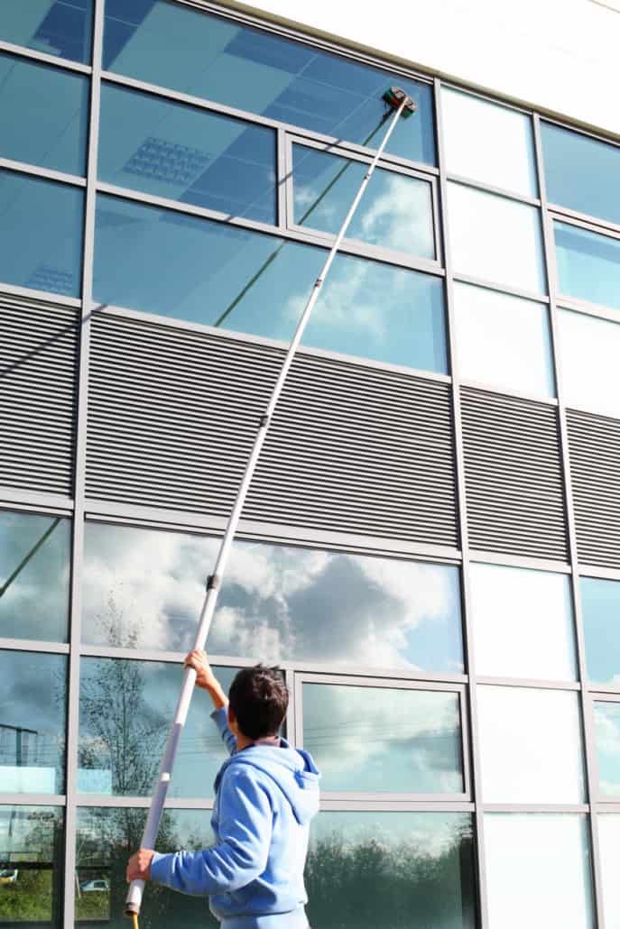 A window cleaner suspended in a harness on a rope system cleans the exterior glass of a large office building.