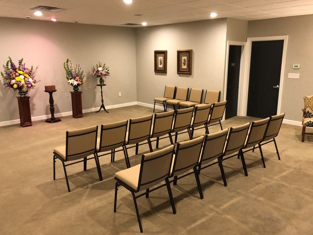 A room with rows of chairs and flowers on the walls.