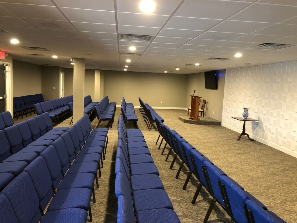 A large room with rows of blue chairs and a podium.
