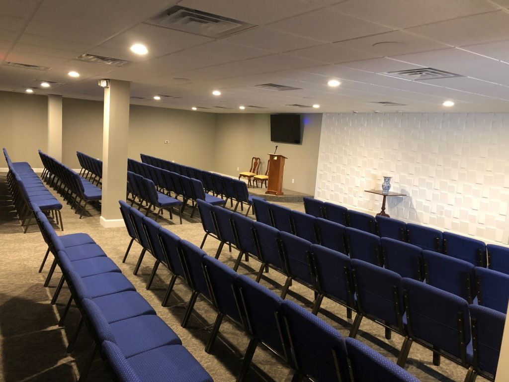 A large room with rows of blue chairs and a podium.