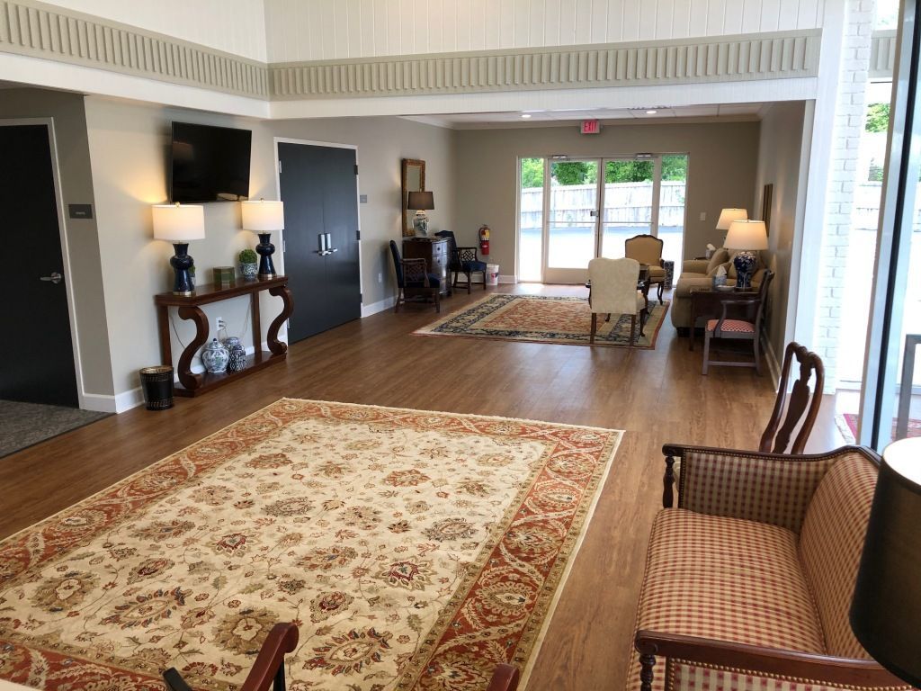 A living room with a couch , chairs , lamps and a rug.