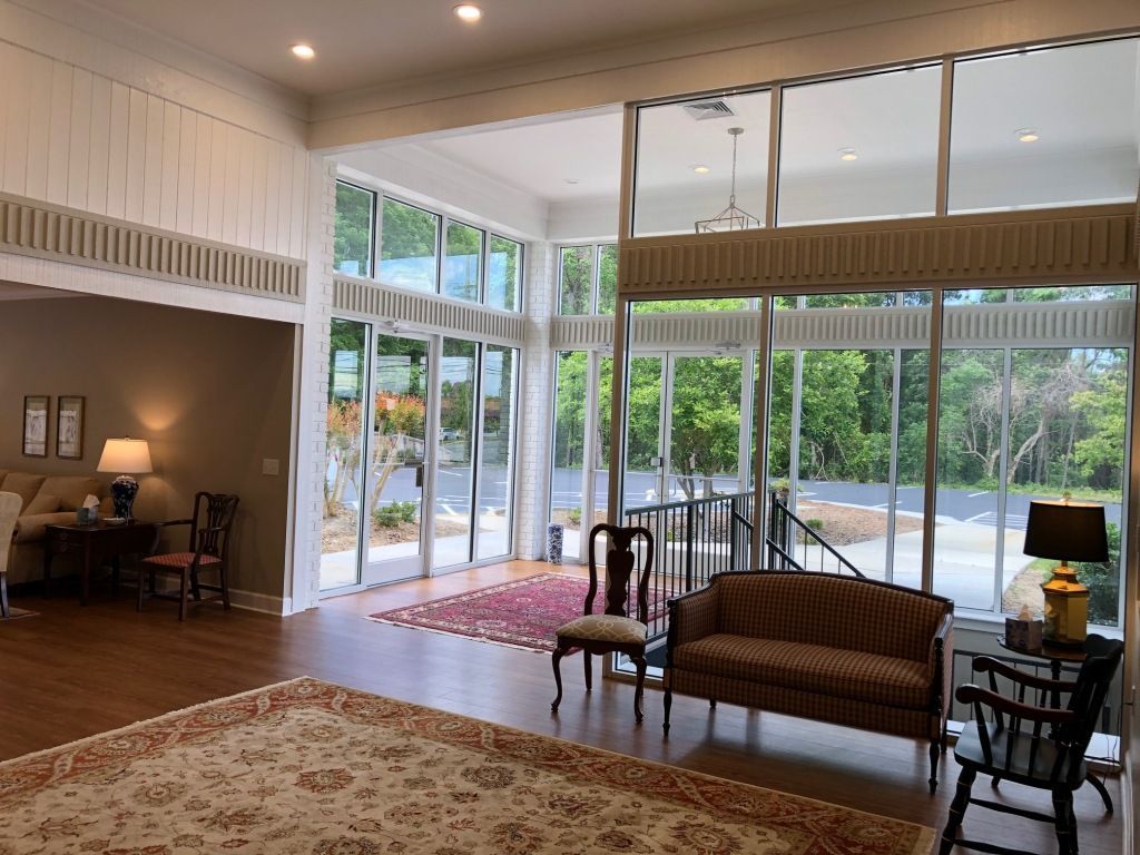 A living room with a couch , chairs , lamps and a large window.