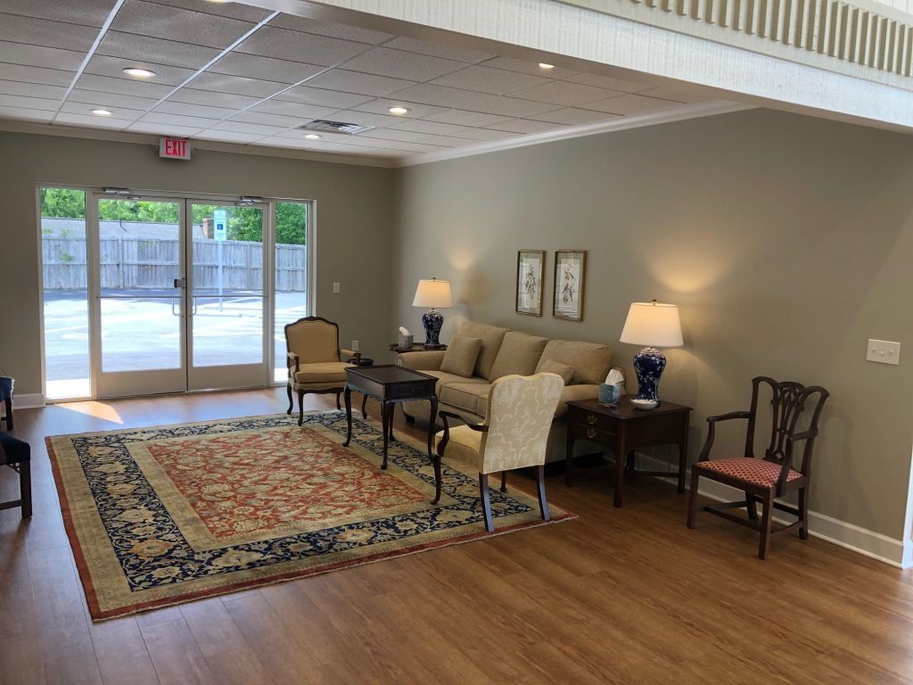 A living room with a couch , chairs , lamps and a rug.