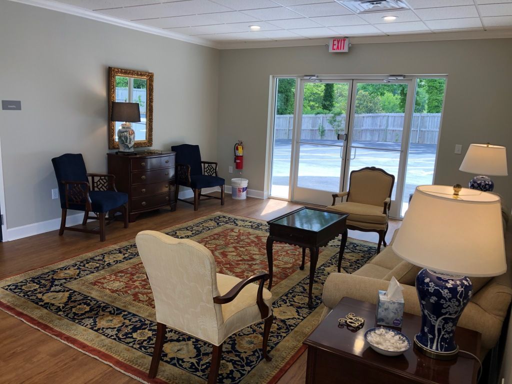 A living room with a couch , chairs , lamps and a rug.