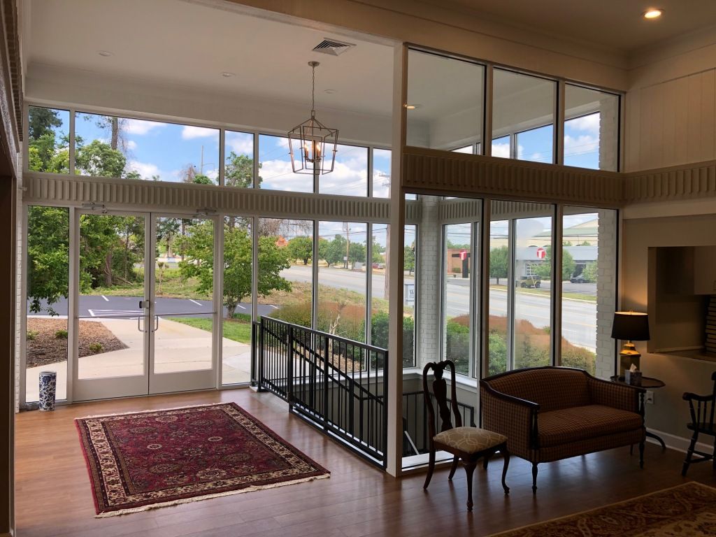 A living room with a couch , chair , rug and lots of windows.
