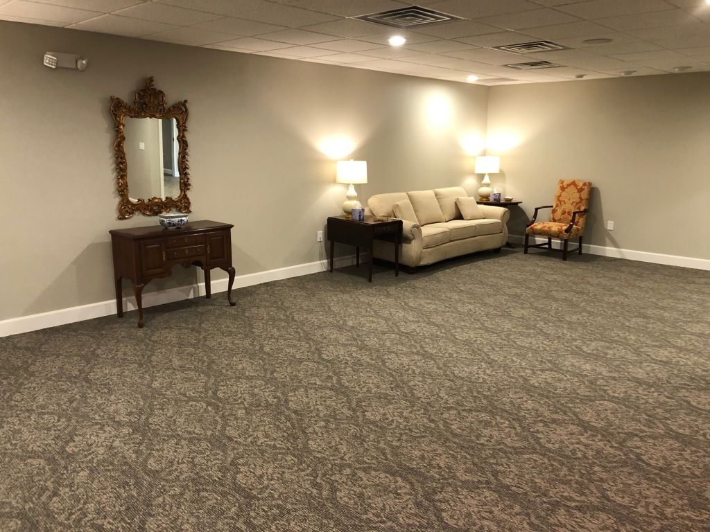A living room with a couch , chair , table and mirror.