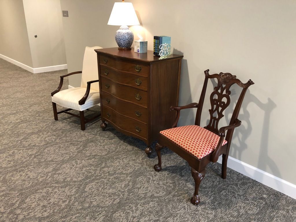 There are two chairs and a dresser in the hallway.