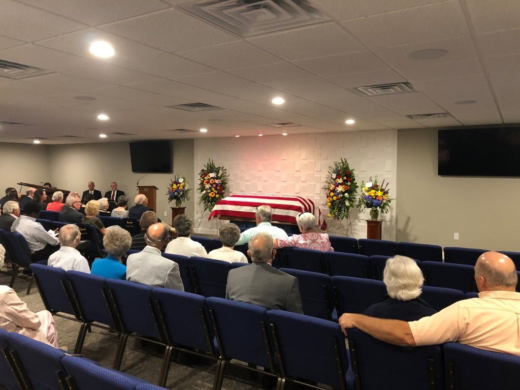 A group of people are sitting in a church watching a funeral.