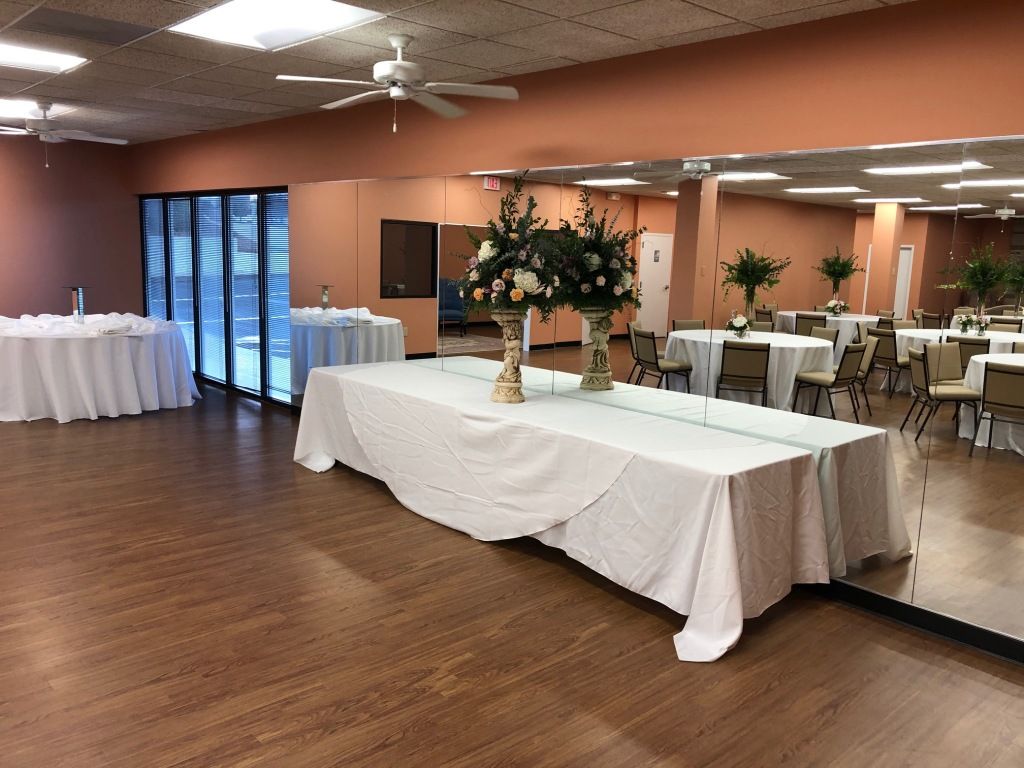 A large room with tables and chairs and a vase of flowers on the table.