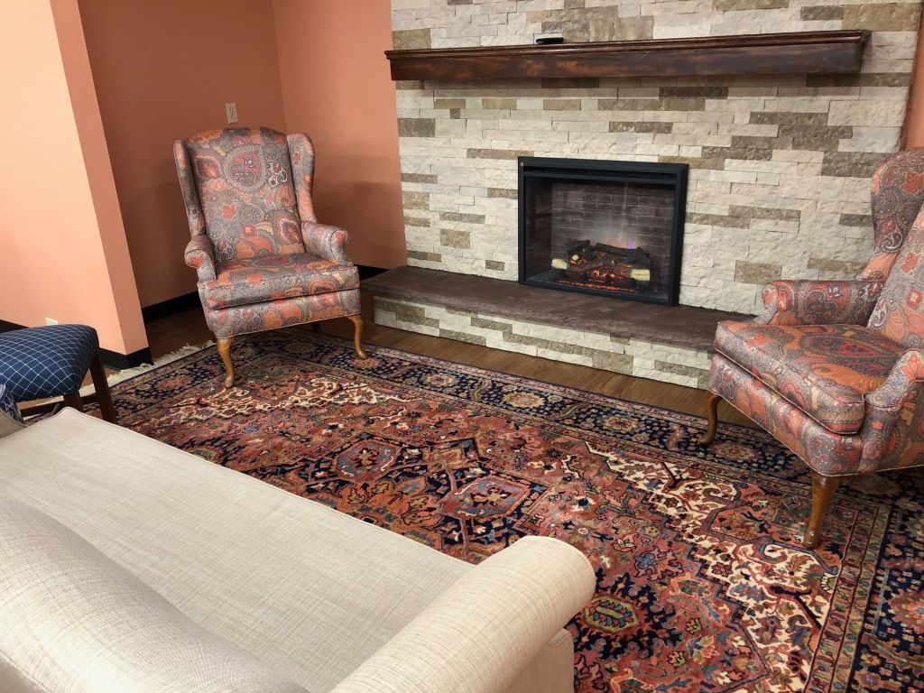 A living room with a couch , chairs and a fireplace.