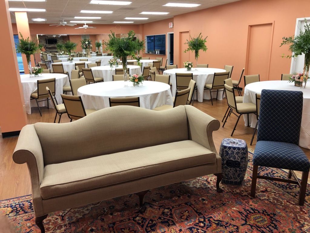 A couch is sitting in a room with tables and chairs.