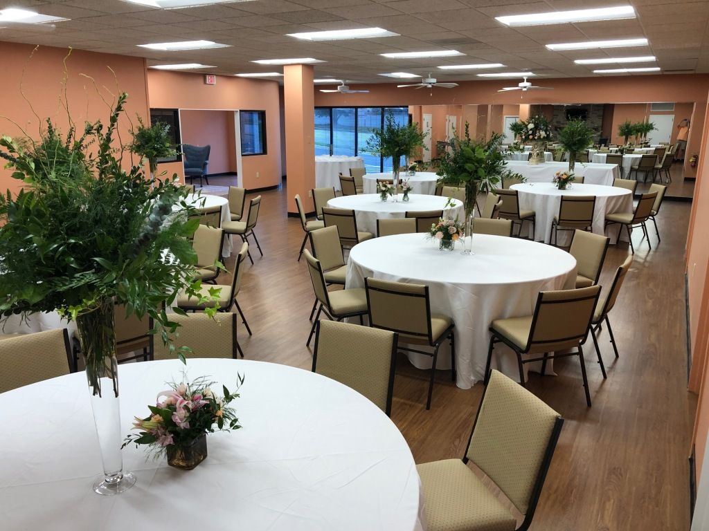 A large room with tables and chairs set up for a wedding reception.