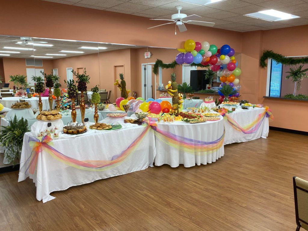 A room filled with tables and balloons decorated for a party.