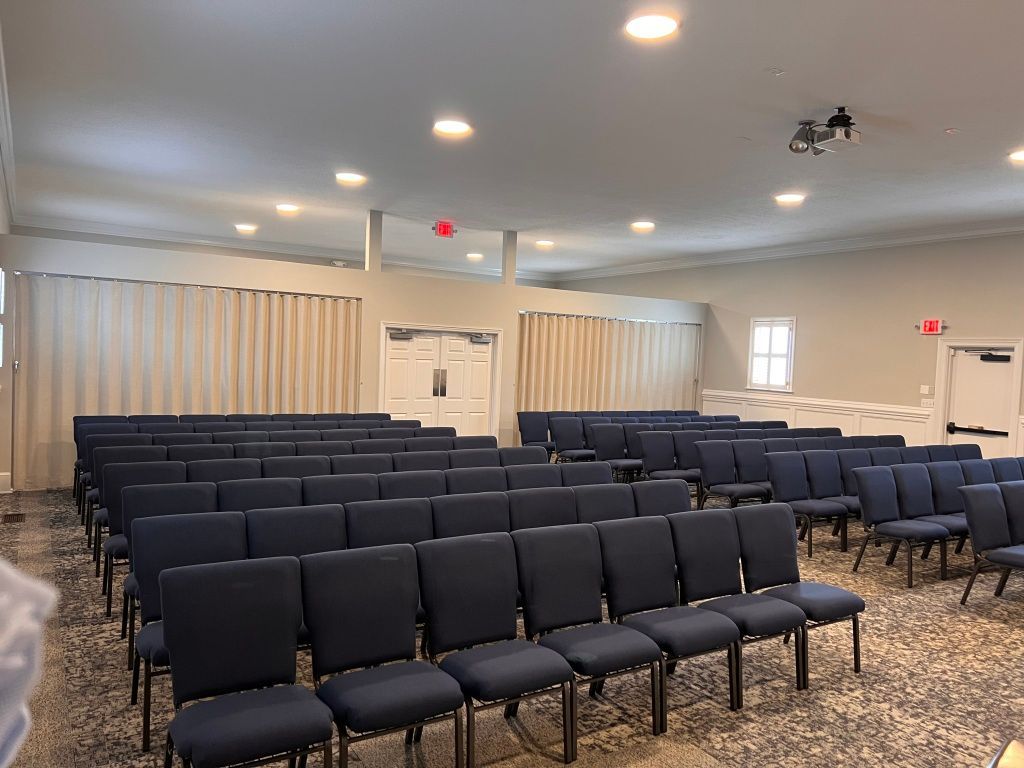 Rows of blue chairs are lined up in a large room.