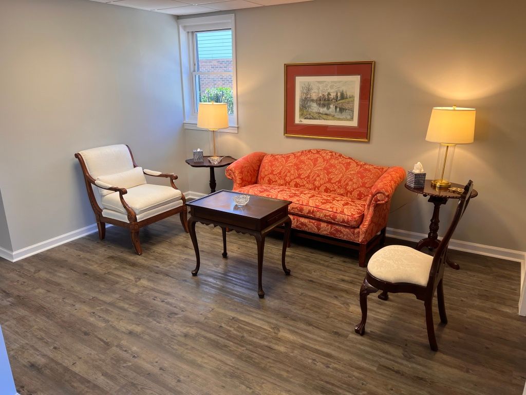 A living room with a couch , chairs , tables and lamps.