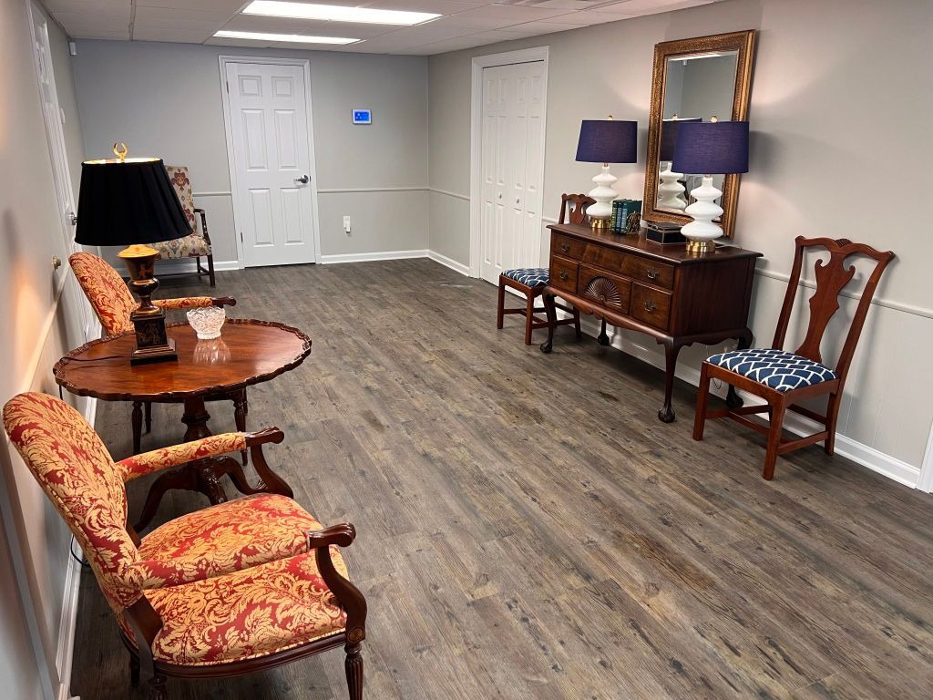 A hallway with chairs , tables , lamps and a mirror.
