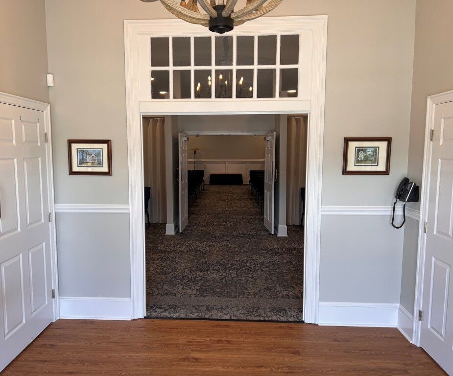 A hallway with hardwood floors and a chandelier hanging from the ceiling