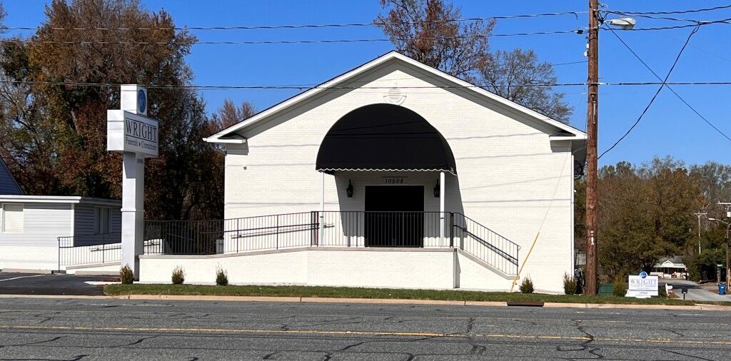 A white building with a black awning is on the side of the road