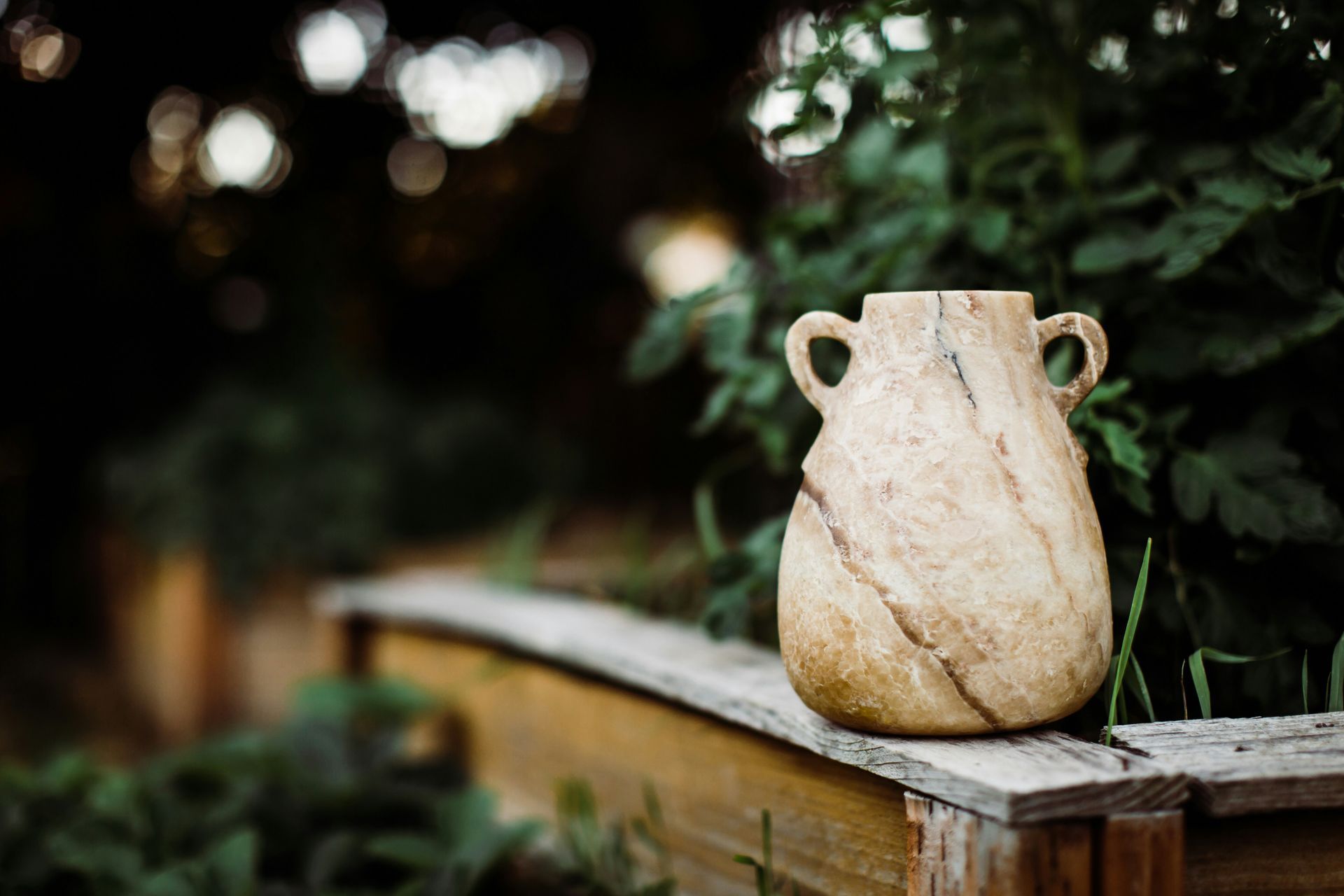 A small vase with two handles is sitting on a wooden table.
