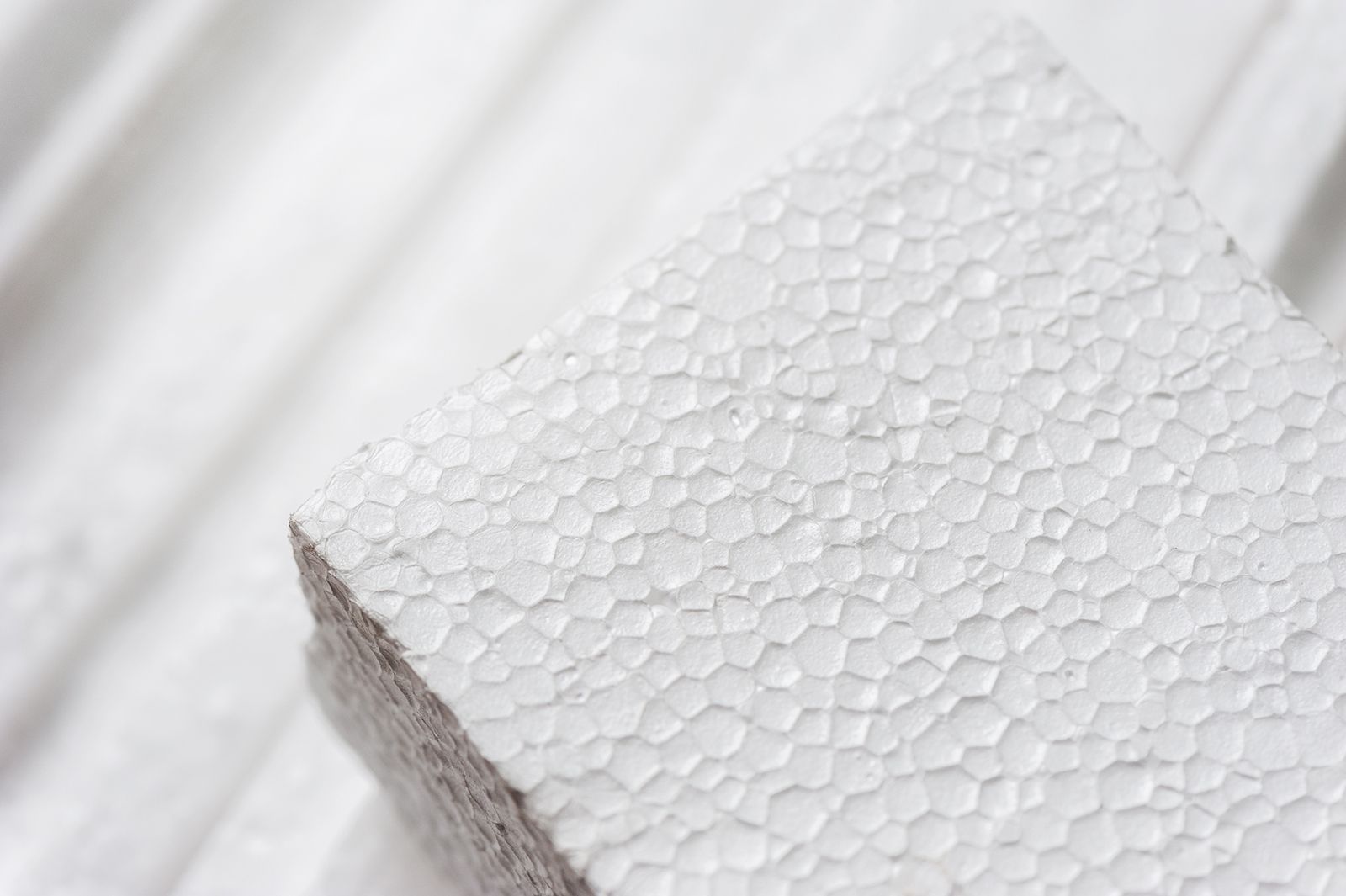 Primer plano de un bloque de espuma blanca con superficie texturizada, sobre un fondo similar.