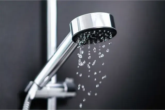 A close up of a shower head with water coming out of it