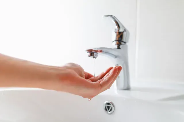 A person is washing their hands in a bathroom sink.