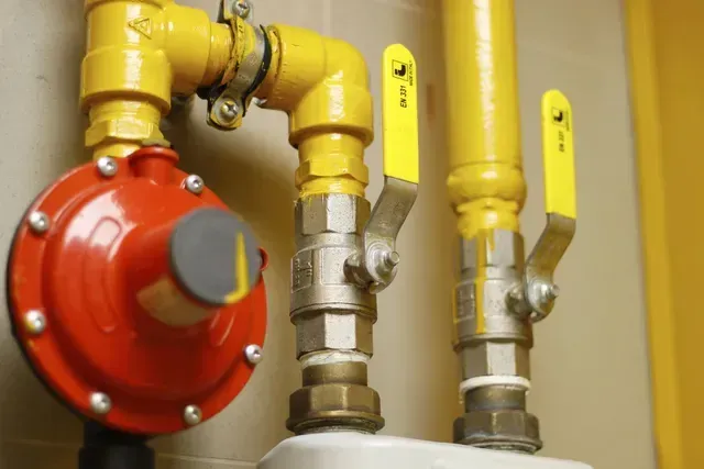 A close up of a gas pipe with yellow valves.