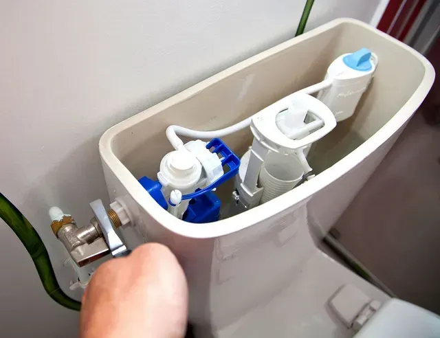 A person is fixing a toilet in a bathroom