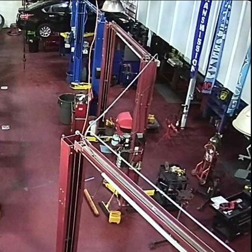 A mechanic's garage with cars on lifts, tools, and equipment; red floor and blue and red lifts | Daytona Automotive