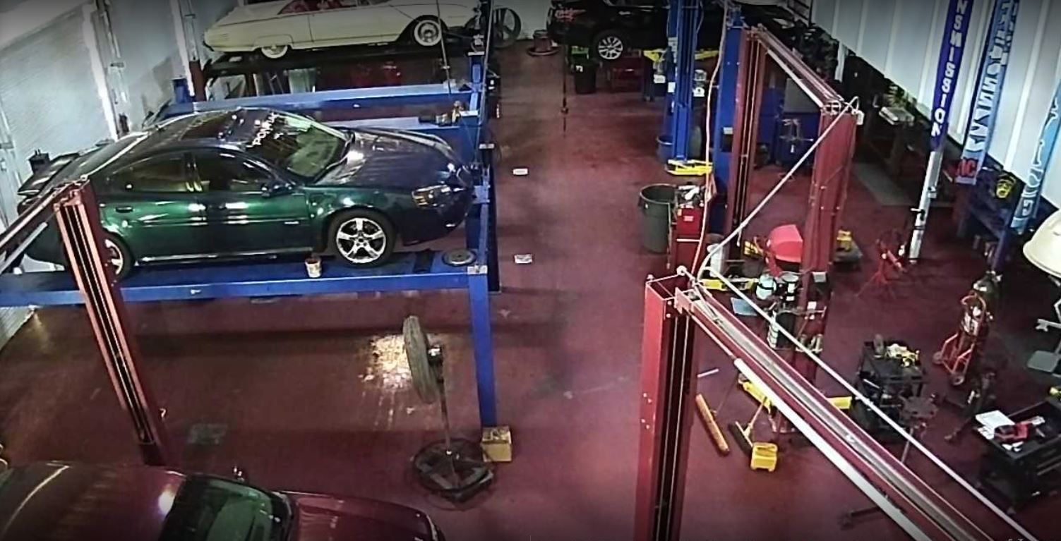 A car repair shop. Several vehicles are raised on lifts. Red floor and blue/red lifts | Daytona Automotive