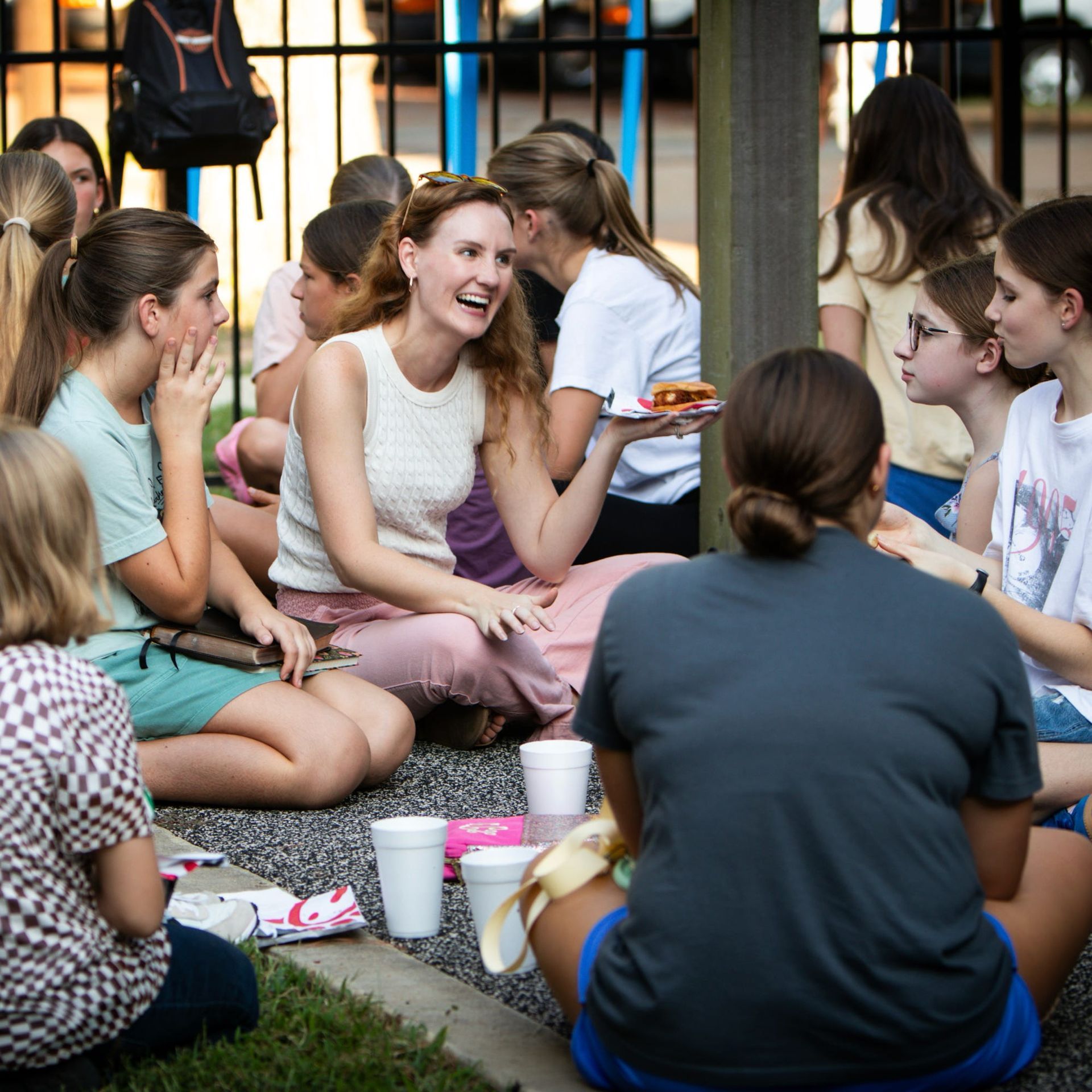 People sitting and eating outdoors, smiling and chatting.