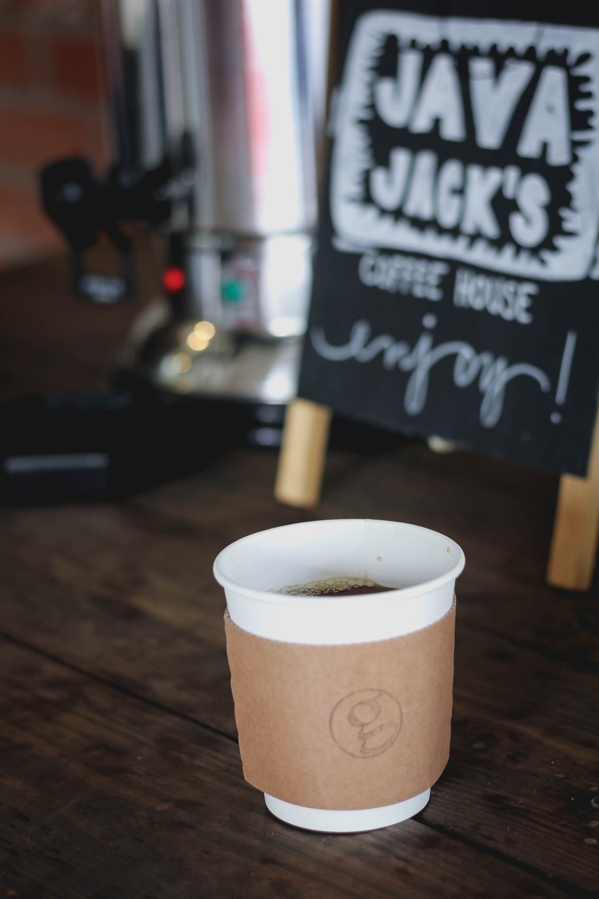 Coffee cup on a wooden table, with a sign for 