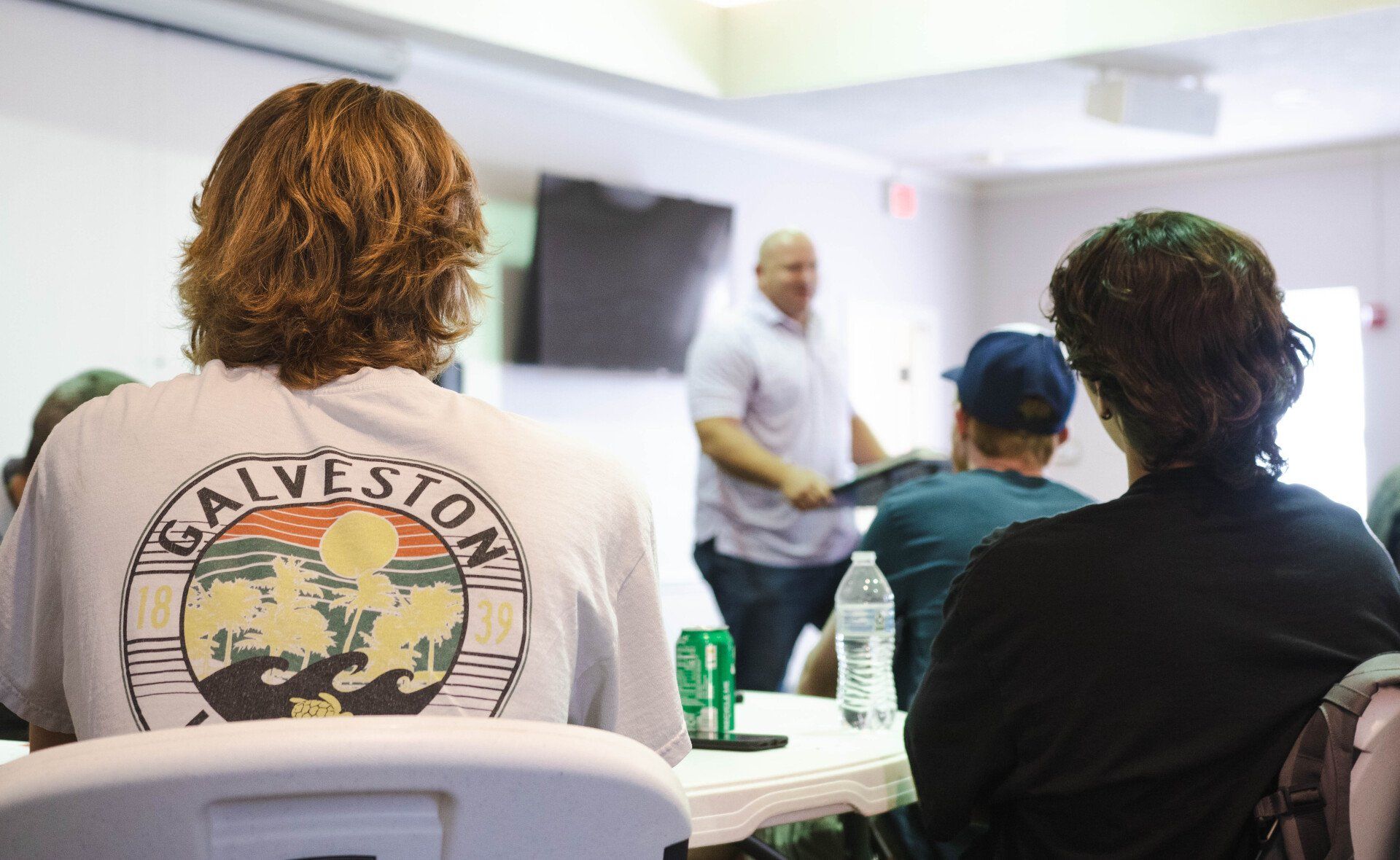 People seated in a room, listening to teaching.
