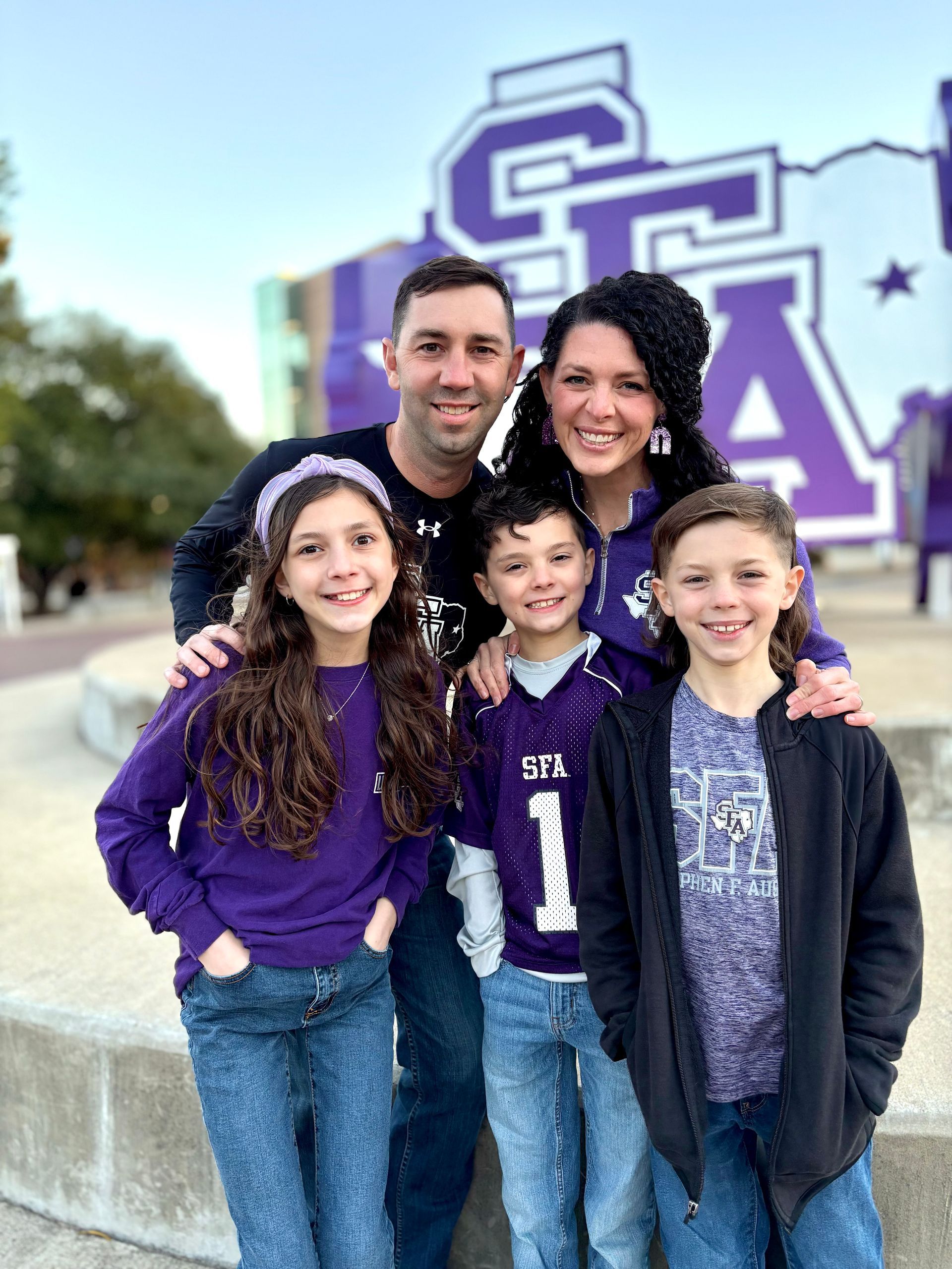 Family of five in front of a purple 