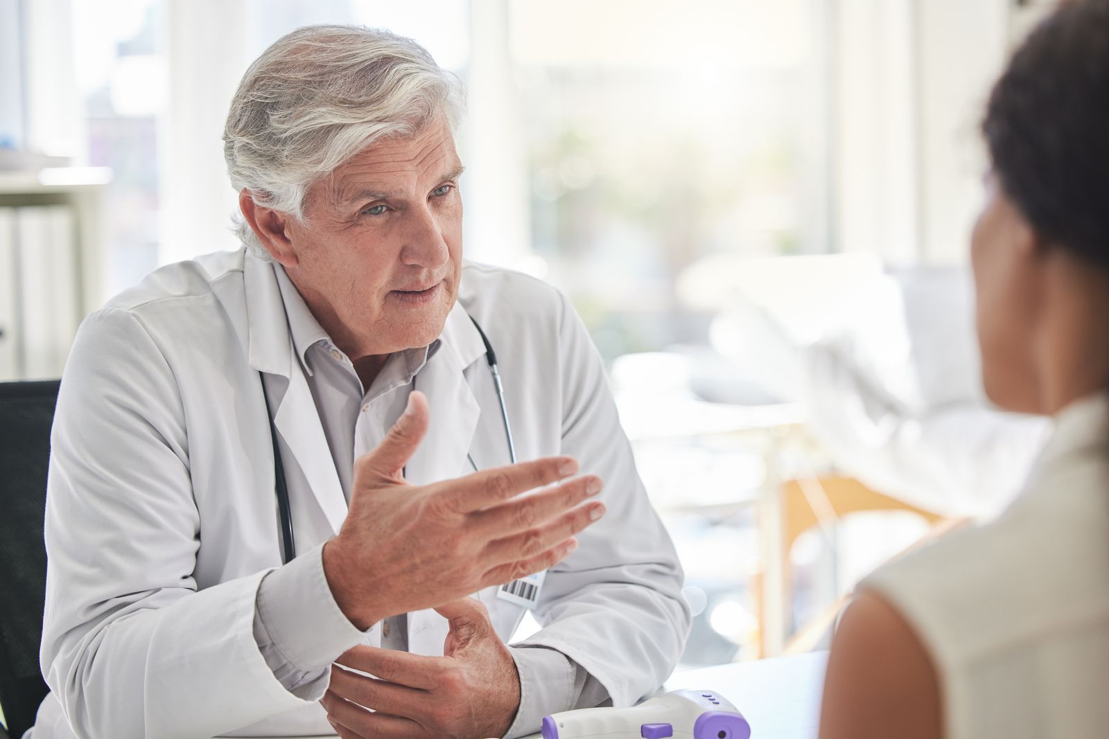 A doctor is talking to a patient while sitting at a desk.