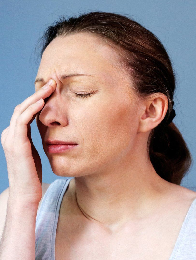 A woman suffering from sinus infection is holding her nose.